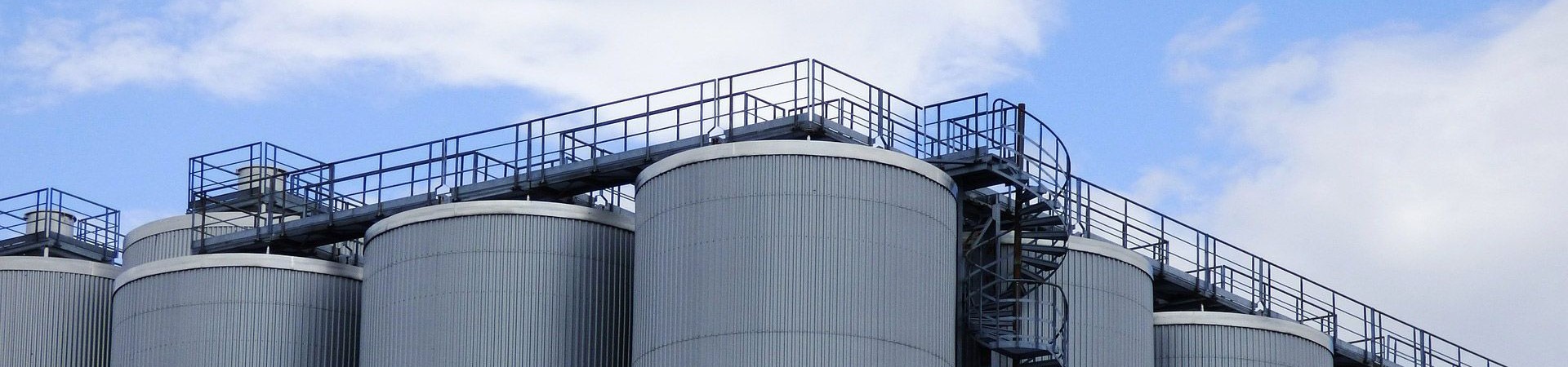 Industrial storage tanks against a cloudy sky.