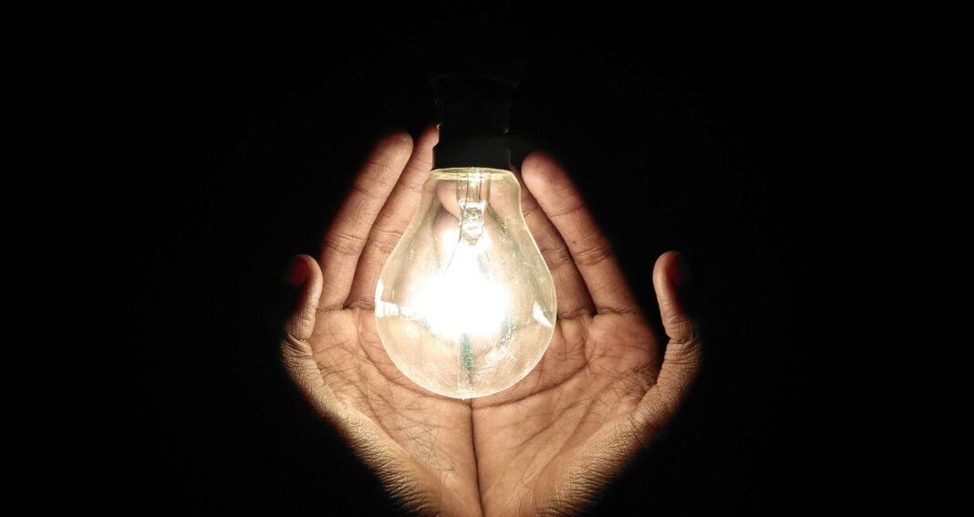 Two hands around a lit lightbulb to illusrate focusing scientific writing on impact