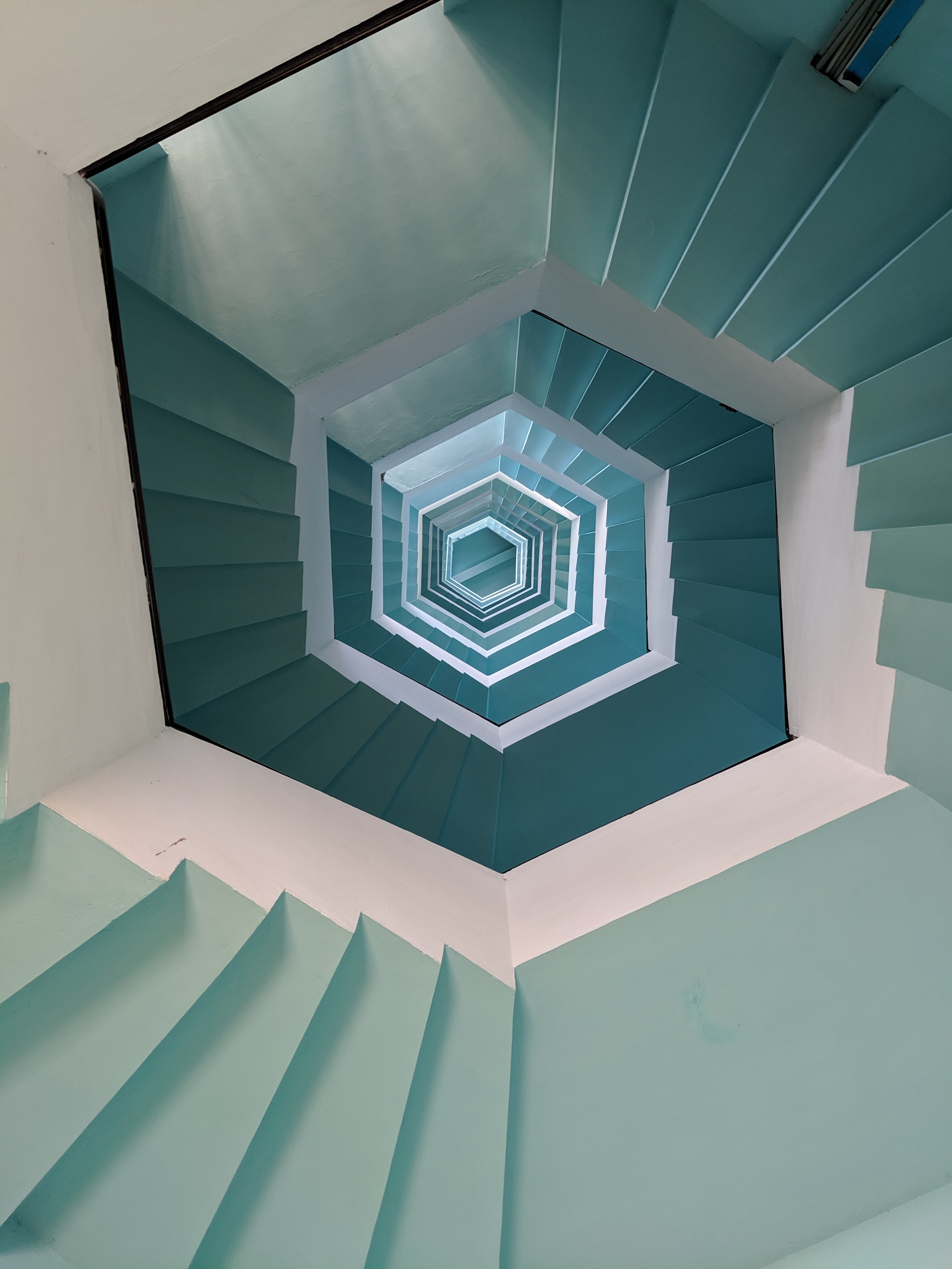 Workplace bullying depicted as a downward spiral staircase in light green and white.