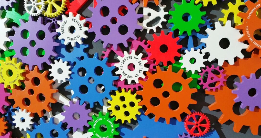 Pile of gears in different sizes and bright colors all lying flat.