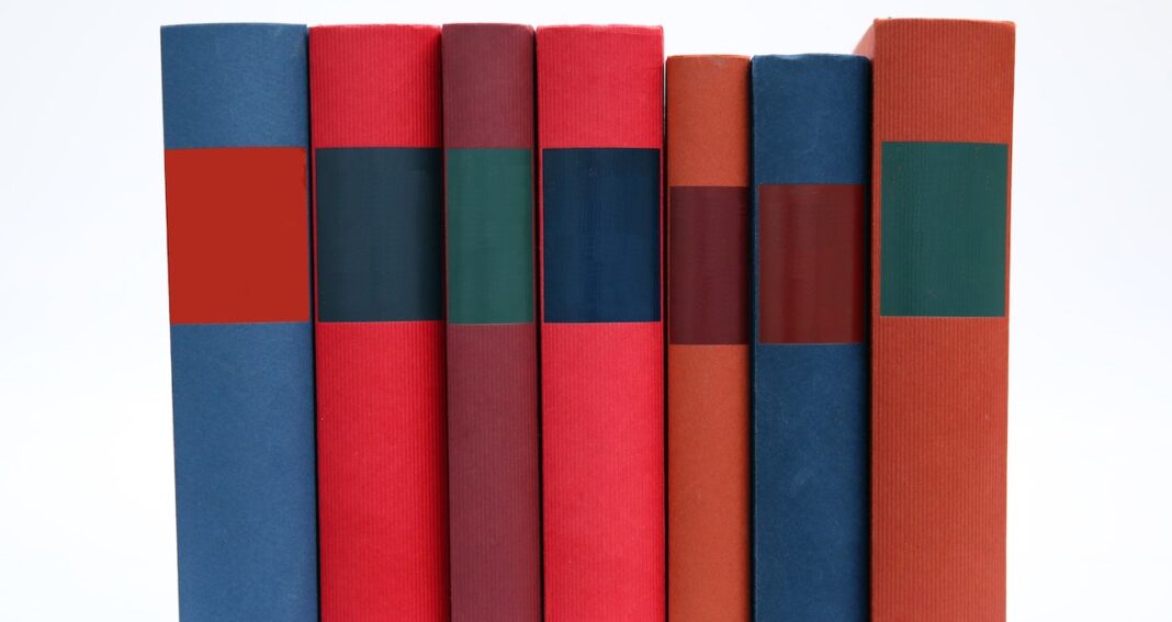 Seven books of different colors in a row.