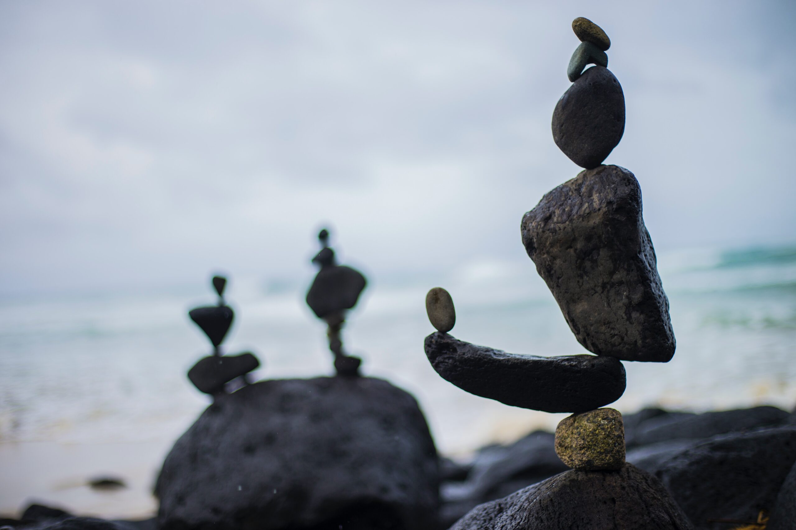 illustrating work-family conflict with three stacks of balancing gray rocks on a beach