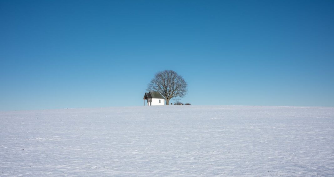 Lonely house and tree in the distance in a desert with a blue sky