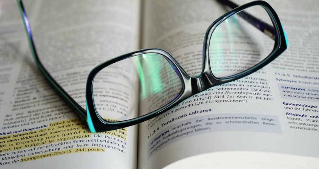 Eye glasses on top of a book suggests a student is trying to maximize their study time.