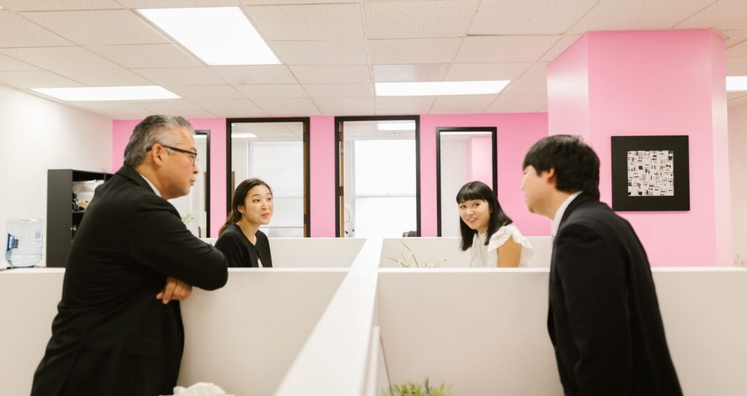 people inside the office standing up in their cubicles and talking